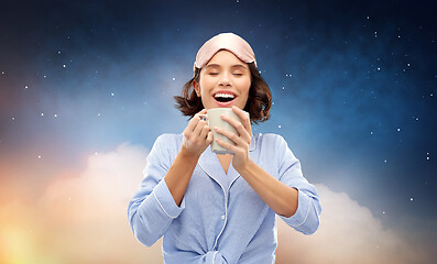 Image showing woman in pajama and sleeping mask drinking coffee