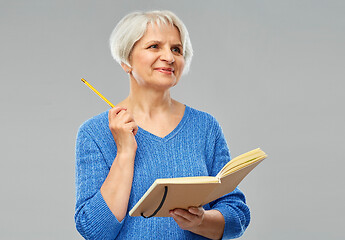 Image showing senior woman with pencil and diary or notebook