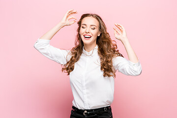 Image showing The happy business woman standing and smiling against pink background.