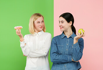 Image showing Diet. Dieting concept. Healthy Food. Beautiful Young Women choosing between fruits and unhelathy cake