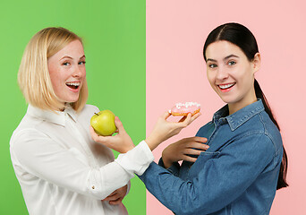 Image showing Diet. Dieting concept. Healthy Food. Beautiful Young Women choosing between fruits and unhelathy cake