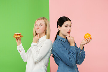 Image showing Diet. Dieting concept. Healthy Food. Beautiful Young Women choosing between fruits and unhelathy fast food