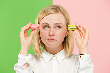 Image showing Young beautiful woman holding macaroons pastry in her hands