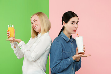 Image showing Diet. Dieting concept. Healthy Food. Beautiful Young Women choosing between fruit orange juice and unhelathy carbonated sweet drink