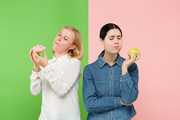 Image showing Diet. Dieting concept. Healthy Food. Beautiful Young Women choosing between fruits and unhelathy cake