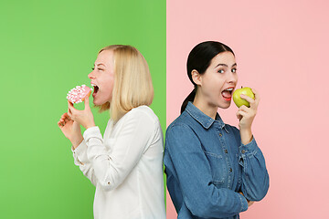 Image showing Diet. Dieting concept. Healthy Food. Beautiful Young Women choosing between fruits and unhelathy cake