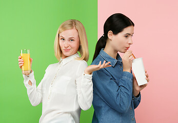 Image showing Diet. Dieting concept. Healthy Food. Beautiful Young Women choosing between fruit orange juice and unhelathy carbonated sweet drink