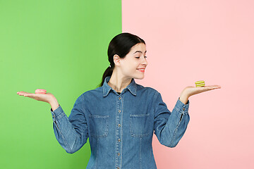 Image showing Young beautiful woman holding macaroons pastry in her hands