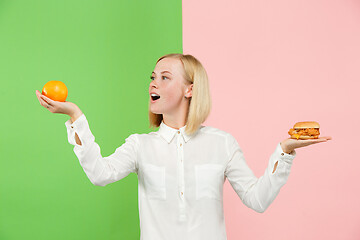 Image showing Diet. Dieting concept. Healthy Food. Beautiful Young Woman choosing between fruits and unhelathy fast food