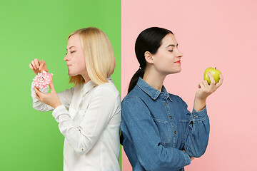 Image showing Diet. Dieting concept. Healthy Food. Beautiful Young Women choosing between fruits and unhelathy cake