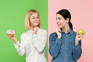 Image showing Diet. Dieting concept. Healthy Food. Beautiful Young Women choosing between fruits and unhelathy cake