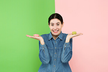 Image showing Young beautiful woman holding macaroons pastry in her hands