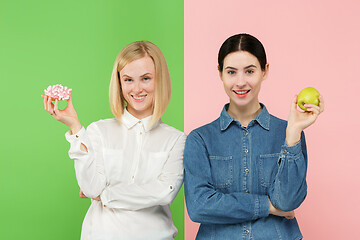 Image showing Diet. Dieting concept. Healthy Food. Beautiful Young Women choosing between fruits and unhelathy cake