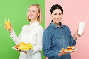 Image showing Diet. Dieting concept. Healthy Food. Beautiful Young Women choosing between fruits and unhelathy fast food