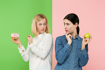 Image showing Diet. Dieting concept. Healthy Food. Beautiful Young Women choosing between fruits and unhelathy cake