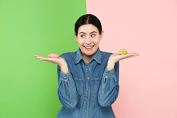 Image showing Young beautiful woman holding macaroons pastry in her hands