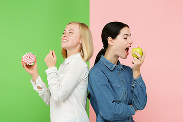 Image showing Diet. Dieting concept. Healthy Food. Beautiful Young Women choosing between fruits and unhelathy cake