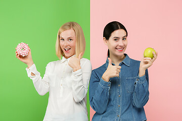 Image showing Diet. Dieting concept. Healthy Food. Beautiful Young Women choosing between fruits and unhelathy cake