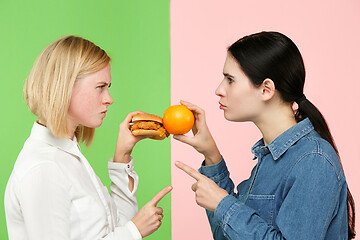 Image showing Diet. Dieting concept. Healthy Food. Beautiful Young Women choosing between fruits and unhelathy fast food