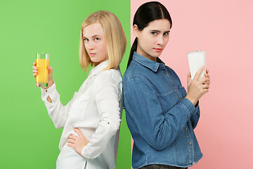 Image showing Diet. Dieting concept. Healthy Food. Beautiful Young Women choosing between fruit orange juice and unhelathy carbonated sweet drink