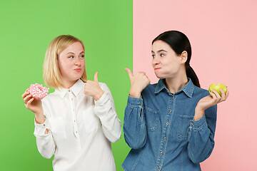 Image showing Diet. Dieting concept. Healthy Food. Beautiful Young Women choosing between fruits and unhelathy cake