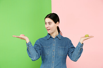 Image showing Young beautiful woman holding macaroons pastry in her hands