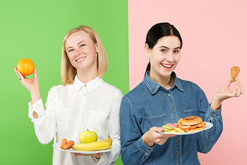 Image showing Diet. Dieting concept. Healthy Food. Beautiful Young Women choosing between fruits and unhelathy fast food