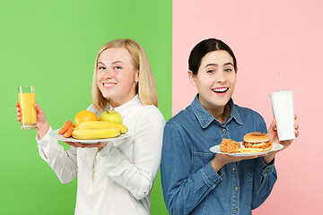 Image showing Diet. Dieting concept. Healthy Food. Beautiful Young Women choosing between fruits and unhelathy fast food