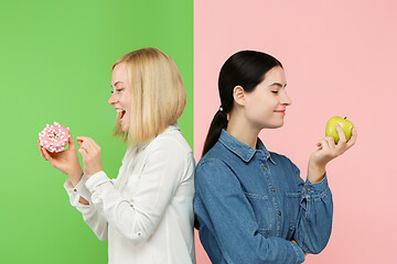 Image showing Diet. Dieting concept. Healthy Food. Beautiful Young Women choosing between fruits and unhelathy cake