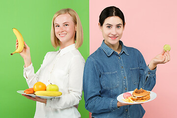 Image showing Diet. Dieting concept. Healthy Food. Beautiful Young Women choosing between fruits and unhelathy fast food