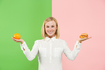 Image showing Diet. Dieting concept. Healthy Food. Beautiful Young Woman choosing between fruits and unhelathy fast food