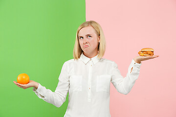 Image showing Diet. Dieting concept. Healthy Food. Beautiful Young Woman choosing between fruits and unhelathy fast food