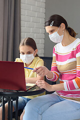 Image showing The girl helps the child to do quarantine lessons