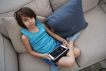 Image showing Little Arabian boy sitting on sofa and playing game on digital t