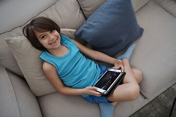 Image showing Little Arabian boy sitting on sofa and playing game on digital t