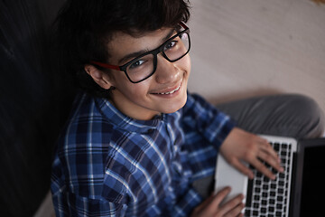 Image showing Arab teenager using laptop to work on homework  at home