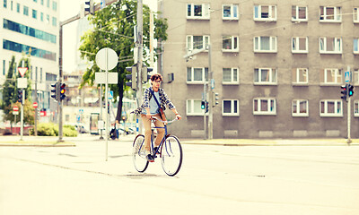 Image showing young hipster man with bag riding fixed gear bike