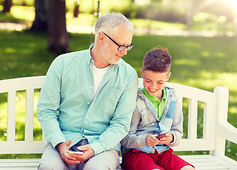 Image showing old man and boy with smartphones at summer park