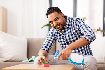 Image showing indian man cleaning table with detergent at home