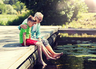 Image showing grandfather and grandson sitting on river berth