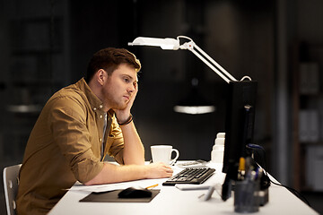 Image showing tired or bored man working late at night office