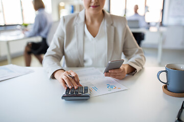 Image showing businesswoman with calculator and smartphone