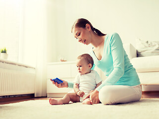 Image showing happy mother showing smartphone to baby at home