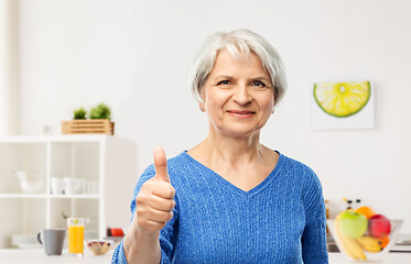 Image showing smiling senior woman showing thumbs up in kitchen