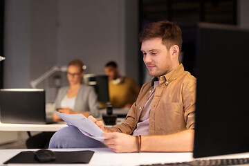 Image showing man with papers working at night office