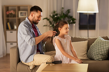 Image showing father braiding daughter hair at home