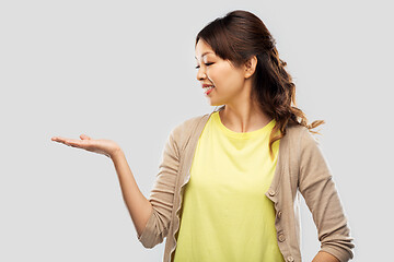 Image showing happy asian woman holding something on hand