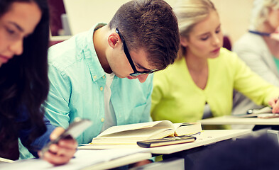 Image showing male student in glasses reading book at lecture