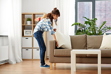 Image showing asian woman arranging sofa cushions at home