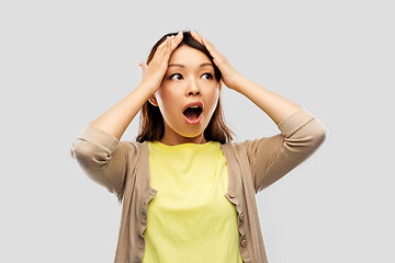 Image showing stressed asian woman holding to her head